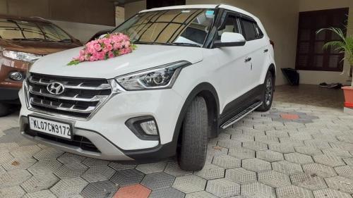 a white car parked in a garage with pink flowers at Athrakkattu Enclave in Trivandrum