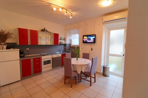 a kitchen with red cabinets and a table with chairs at Seaside Apartment Franica in Vela Luka