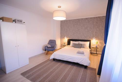 a bedroom with a white bed and a blue chair at Casa de Vacanta Cris in Băile Olăneşti