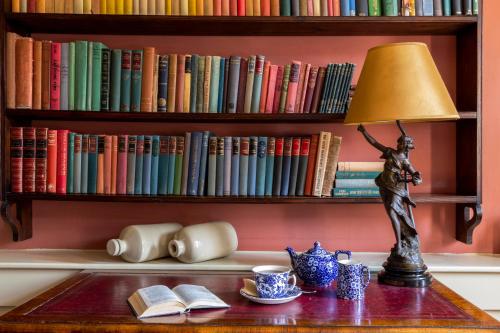 a lamp on a table with books on a shelf at Hazlitt's in London