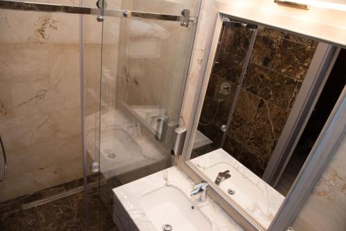 a bathroom with a sink and a shower with a mirror at ART Hotel in Sibiu