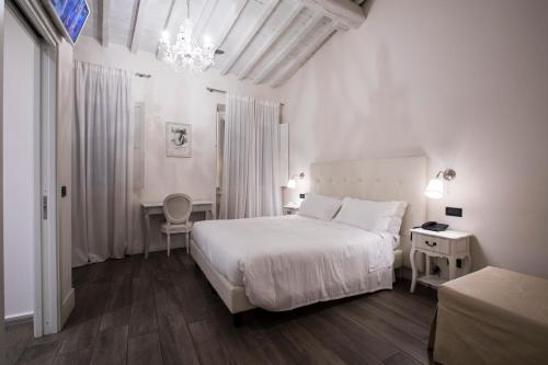 Habitación blanca con cama y lámpara de araña. en Tornabuoni View, en Florencia