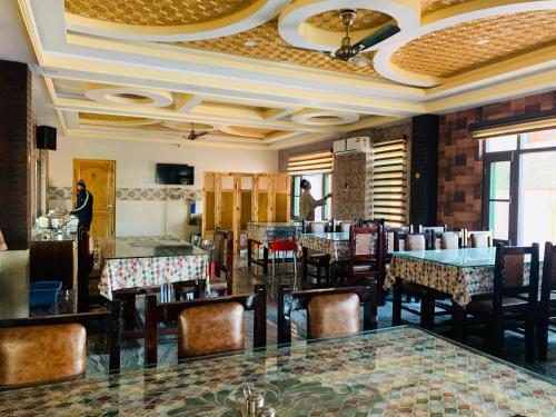 Un restaurante con mesas y sillas en una sala. en Hotel Shuhrah-I-Afaq, en Baghwānpur