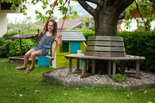 a little girl sitting on a swing around a tree at Pension Kumbichlhof in Mayrhofen