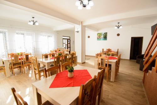 a restaurant with wooden tables and chairs and red napkins at Vila Moecel in Moieciu de Sus