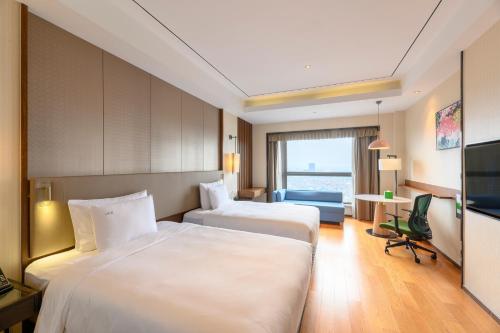a hotel room with two beds and a television at Holiday Inn Kunshan by IHG in Kunshan