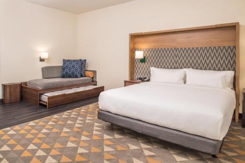 a hotel room with a bed and a chair at Holiday Inn Joplin by IHG in Joplin