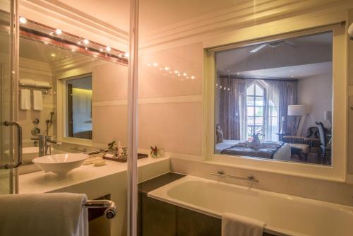 a bathroom with a tub and a sink and a mirror at Caravela Beach Resort in Varca