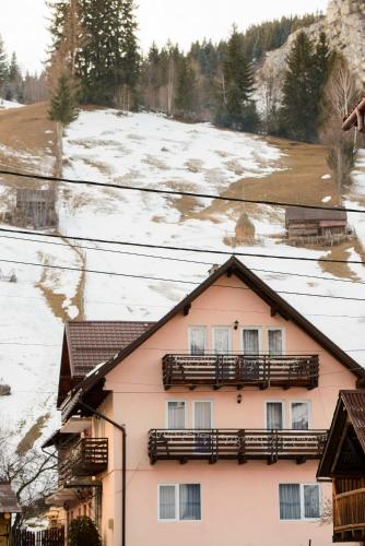 a pink house with wooden balconies and snow at Vila Moecel in Moieciu de Sus