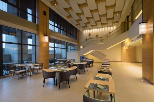 a dining room with tables and chairs and windows at Holiday Inn Kunshan Huaqiao by IHG in Kunshan