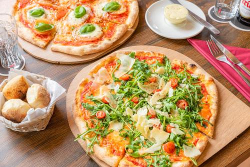 two pizzas sitting on top of a wooden table at Kölnotel Hostel, Apart & Suite in Cologne