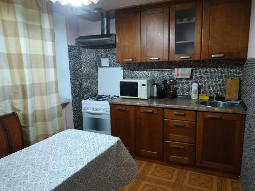 eine kleine Küche mit einem Herd und einer Mikrowelle in der Unterkunft Nice apartment near Gulliver in Kiew