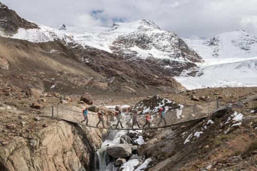 a group of people crossing a bridge over a waterfall at Meublè Garnì Della Contea in Bormio