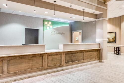 a lobby with a reception desk and a mirror at Holiday Inn Lafayette-City Centre by IHG in Lafayette
