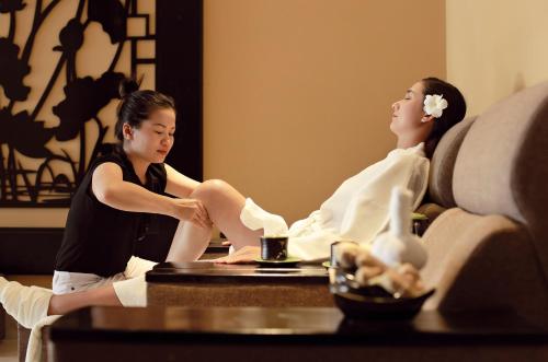 a woman sitting on a couch in front of a man at Royal Riverside Hoi An Hotel & Spa in Hoi An