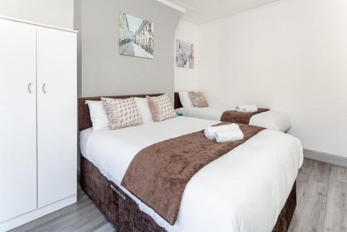 a bedroom with two beds with white walls at Superb Spacious House For Contractors & Families & Private Parking By Liverpool Short Stay in Liverpool