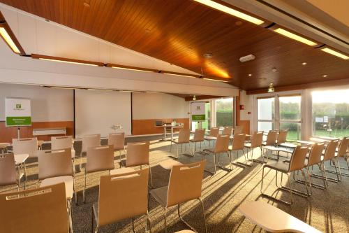 a classroom with tables and chairs in a room at Holiday Inn Lille Ouest Englos by IHG in Englos