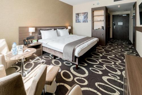 a hotel room with a bed and a desk and chairs at Holiday Inn Dąbrowa Górnicza-Katowice by IHG in Dąbrowa Górnicza