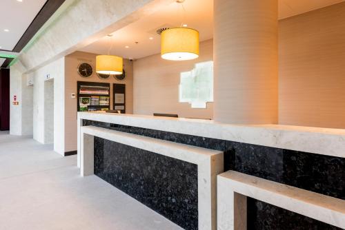 a lobby with a long counter and two lights at Holiday Inn Dąbrowa Górnicza-Katowice by IHG in Dąbrowa Górnicza