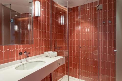 a red tiled bathroom with a sink and a mirror at Room Mate Macarena, Madrid Gran Vía in Madrid