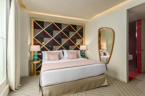 1 dormitorio con 1 cama grande y espejo grande en Room Mate Macarena – Gran Vía en Madrid