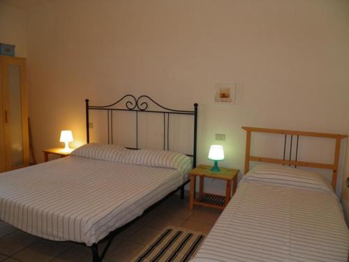 two beds in a room with two lamps on tables at MaremMare Tuscany Apartments in Principina a Mare