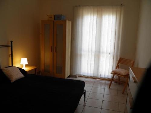 a bedroom with a bed and a chair and a window at MaremMare Tuscany Apartments in Principina a Mare