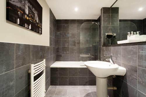 ein Badezimmer mit einem Waschbecken und einer Badewanne in der Unterkunft Veeve - River Views from Vauxhall in London