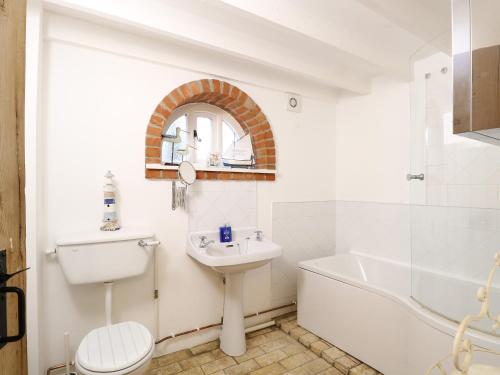 uma casa de banho com um lavatório, uma banheira e um WC. em Stable Cottage em West Bradenham