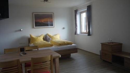 um quarto com uma cama com almofadas amarelas e uma mesa em Weinbau Ettenauer em Rohrendorf bei Krems