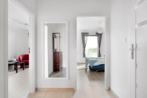 a white hallway with a mirror and a bedroom at Elite Apartments Nadmorski Brzeźno in Gdańsk