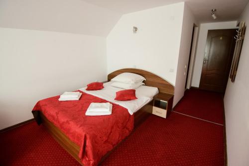 a bedroom with a bed with red sheets and pillows at Vila Moecel in Moieciu de Sus