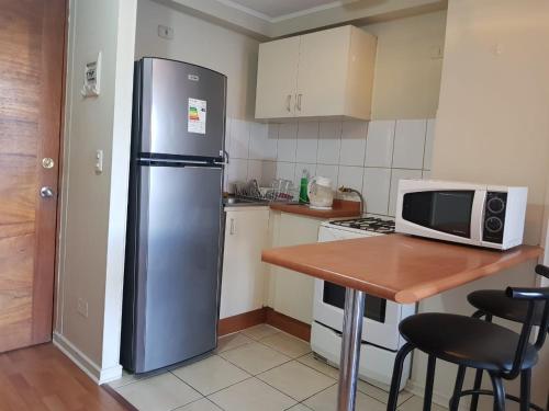 a kitchen with a stainless steel refrigerator and a table at Departamento A Pasos de Metro Ñuble in Santiago