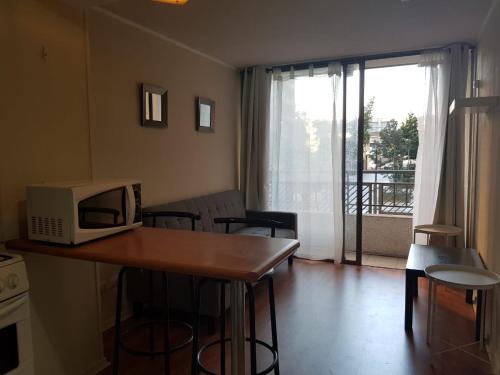 a kitchen with a table with a microwave and a living room at Departamento A Pasos de Metro Ñuble in Santiago
