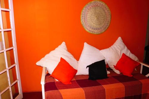 a bedroom with an orange wall and a bed with pillows at Casas Caminho Do Meio in Lençóis