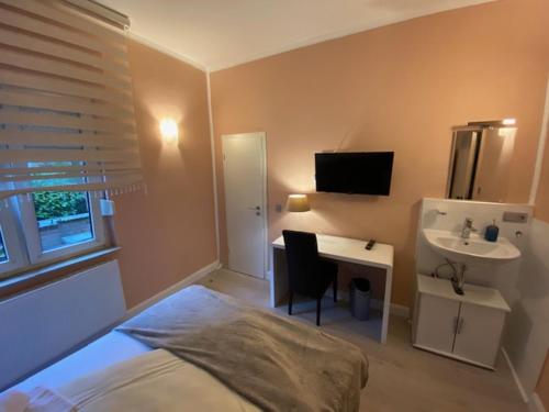 a bedroom with a bed and a desk and a sink at Hotel Sophia in Warendorf