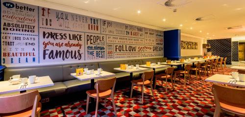 a restaurant with a row of tables and chairs at Holiday Inn Leeds Garforth by IHG in Garforth