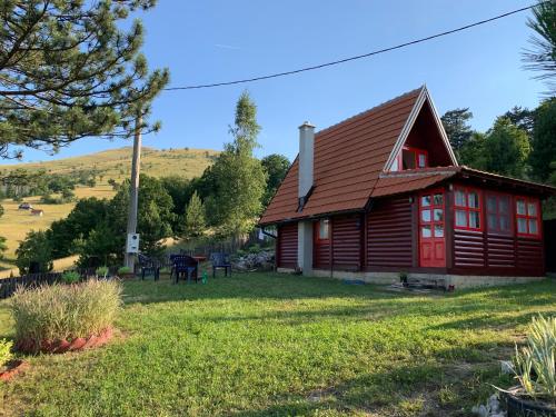 una cabaña de madera con una puerta roja en un patio en Brvnara ispod Čigote en Zlatibor