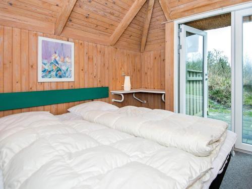 ein großes weißes Bett in einem Holzzimmer mit Fenster in der Unterkunft Four-Bedroom Holiday home in Vejers Strand 9 in Vejers Strand