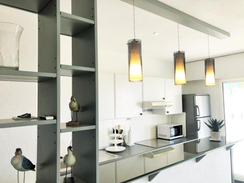 - une cuisine avec des murs blancs, des armoires et des lumières grises dans l'établissement PALMA T3 confort parking centre, à Arcachon