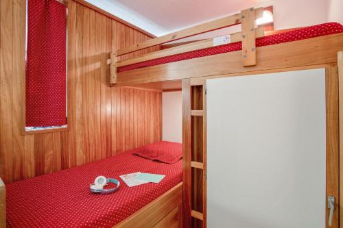 サン・シャフレにあるPierre et Vacances Serre Chevalier Chantemerleの赤いシーツを使用した二段ベッドが備わる小さな客室です。