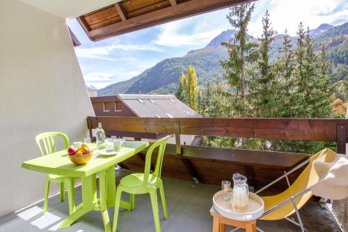 a green table and chairs on a balcony with a view at Pierre et Vacances Serre Chevalier Chantemerle in Saint-Chaffrey