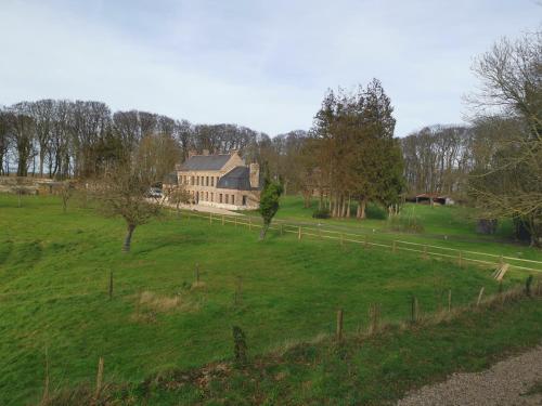 a large house in a field with a fence at Manoir des Carreaux Chambres d'hôtes in Ingouville