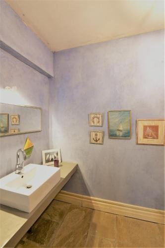 a bathroom with a white sink and paintings on the wall at The Seacret Beachfront Villa in Nea Peramos