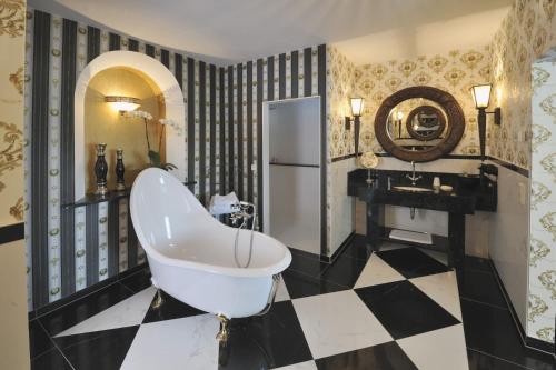 ein Badezimmer mit einer Badewanne und einem schwarz-weiß karierten Boden in der Unterkunft Landhaus Hotel Romantik in Gotha