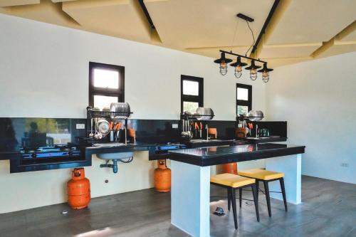 a kitchen with a counter with stools in it at Rold and Roub Home Suites powered by Cocotel in Puerto Galera