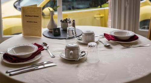 a white table with plates and silverware on it at Portland House in Keswick