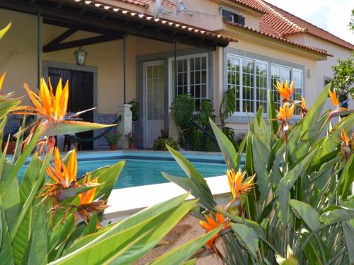 a house with a pool and flowers in front of it at Quinta do Covanco in Alenquer