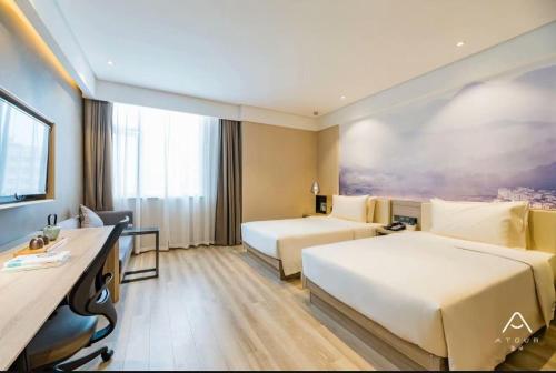 una camera d'albergo con due letti e una scrivania di Atour Hotel Hangzhou Qianjiang New Town Qingchun Plaza a Hangzhou