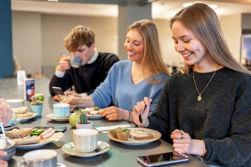 a group of people sitting around a table eating food at a&o München Laim in Munich